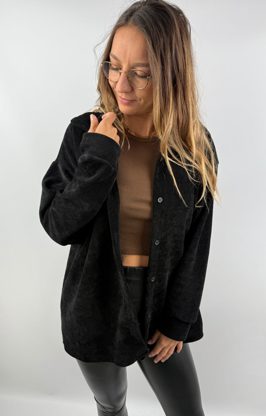 Frau trägt ein schwarzes Cordhemd über einem braunen Top – lässiger, offener Look.