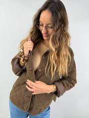 Frau trägt eine braune gesteppte Cordjacke mit Druckknöpfen, kombiniert mit einem beigen Ripp-Top – gemütlicher Look in warmen Naturtönen.
