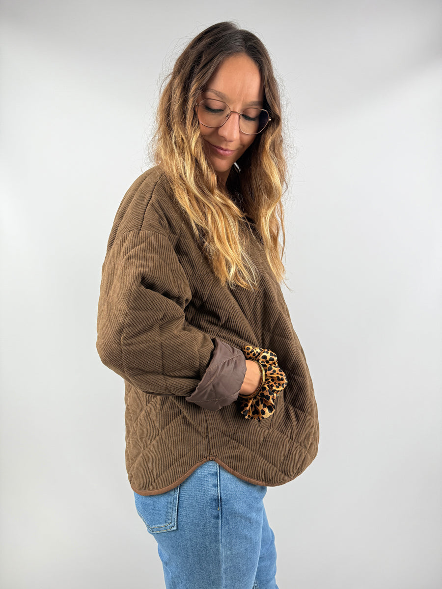 Seitenansicht der braunen, gesteppten Cordjacke mit Kontrastfutter – lässig kombiniert mit Jeans und goldenen Accessoires.