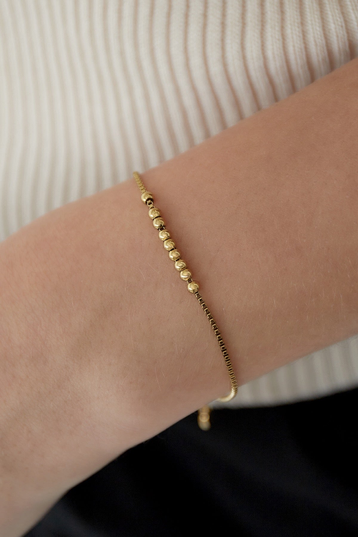 Vergoldetes Kugel-Armband in Nahaufnahme auf weißem Hintergrund.