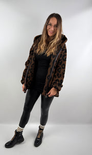Frau trägt eine dunkelbraune Leo Teddy Jacke mit Leo-Print, kombiniert mit schwarzer Lederleggings und Boots.
