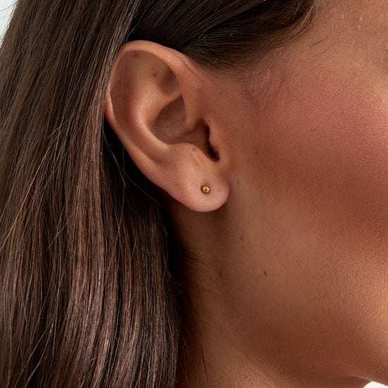 Dezente kugelförmige Ohrstecker aus vergoldetem Edelstahl am Ohr getragen