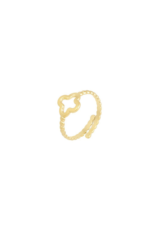 Gedrehter Ring mit Kleeblatt in Gold auf hellem Hintergrund – minimalistischer Schmuck mit feinem Glanz.