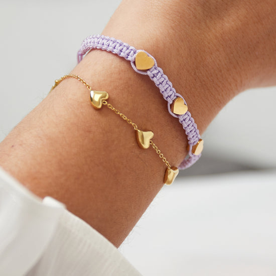 Flieder farbenes Makrame Armband mit drei goldenen Edelstahl Herzen.