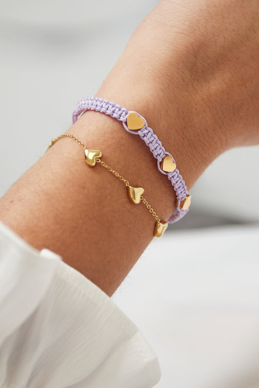 Flieder farbenes Makrame Armband mit drei goldenen Edelstahl Herzen.