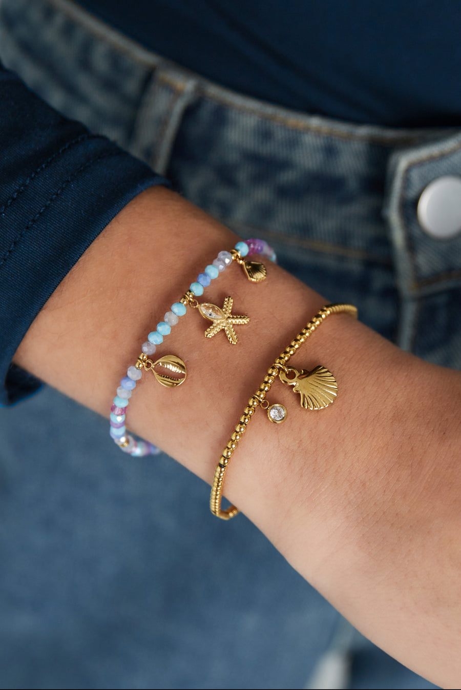 Edelstahl Armband mit Glas und Naturstein Perlen und goldenen Edelstahlanhängern im maritimen Design in pastelligen Lila und Blau Tönen.