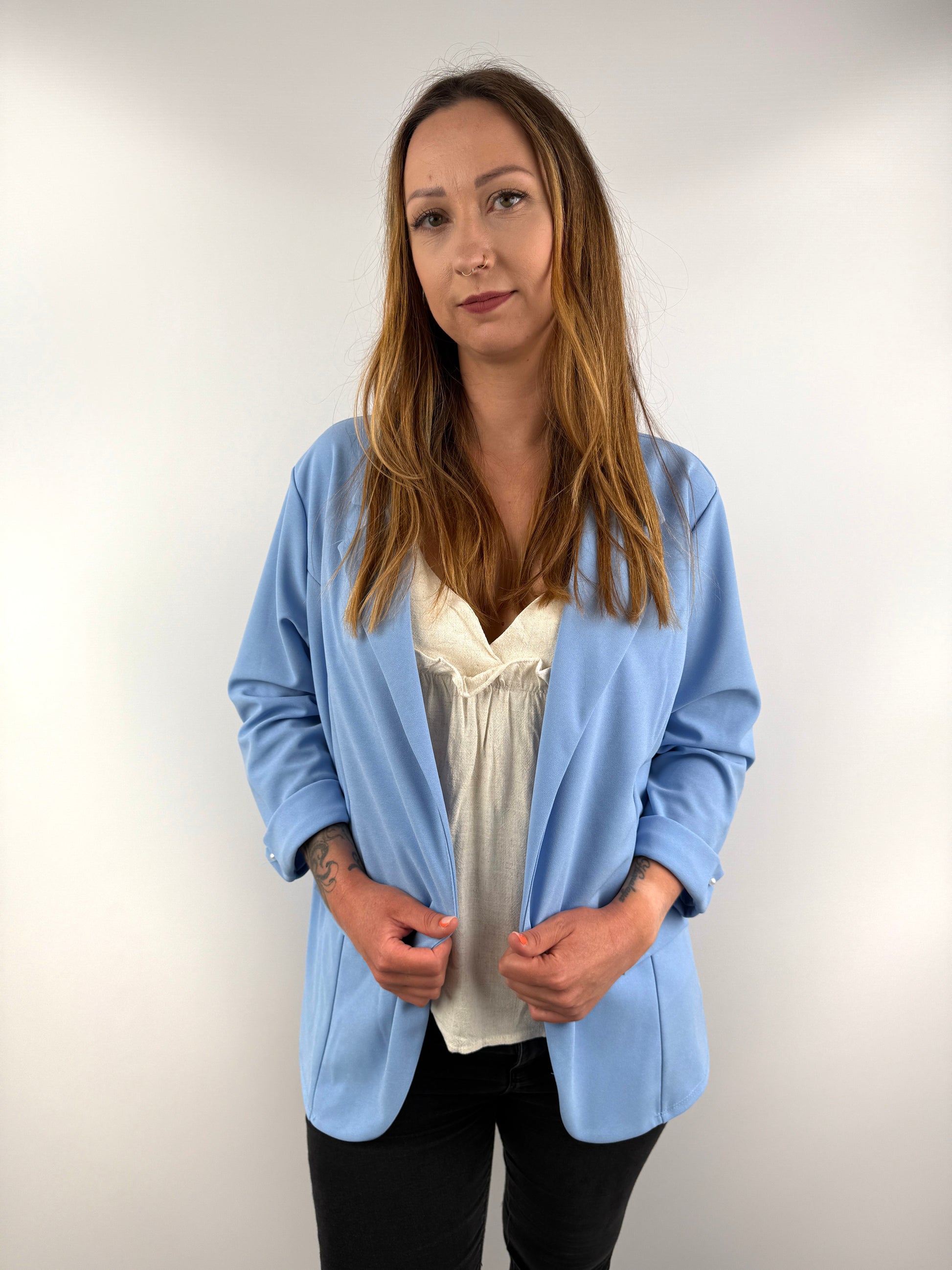 Hellblauer Blazer mit umgeschlagenen Ärmeln und Perlenknopf-Detail.