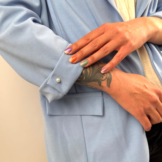 Hellblauer Blazer mit umgeschlagenen Ärmeln und Perlenknopf-Detail.