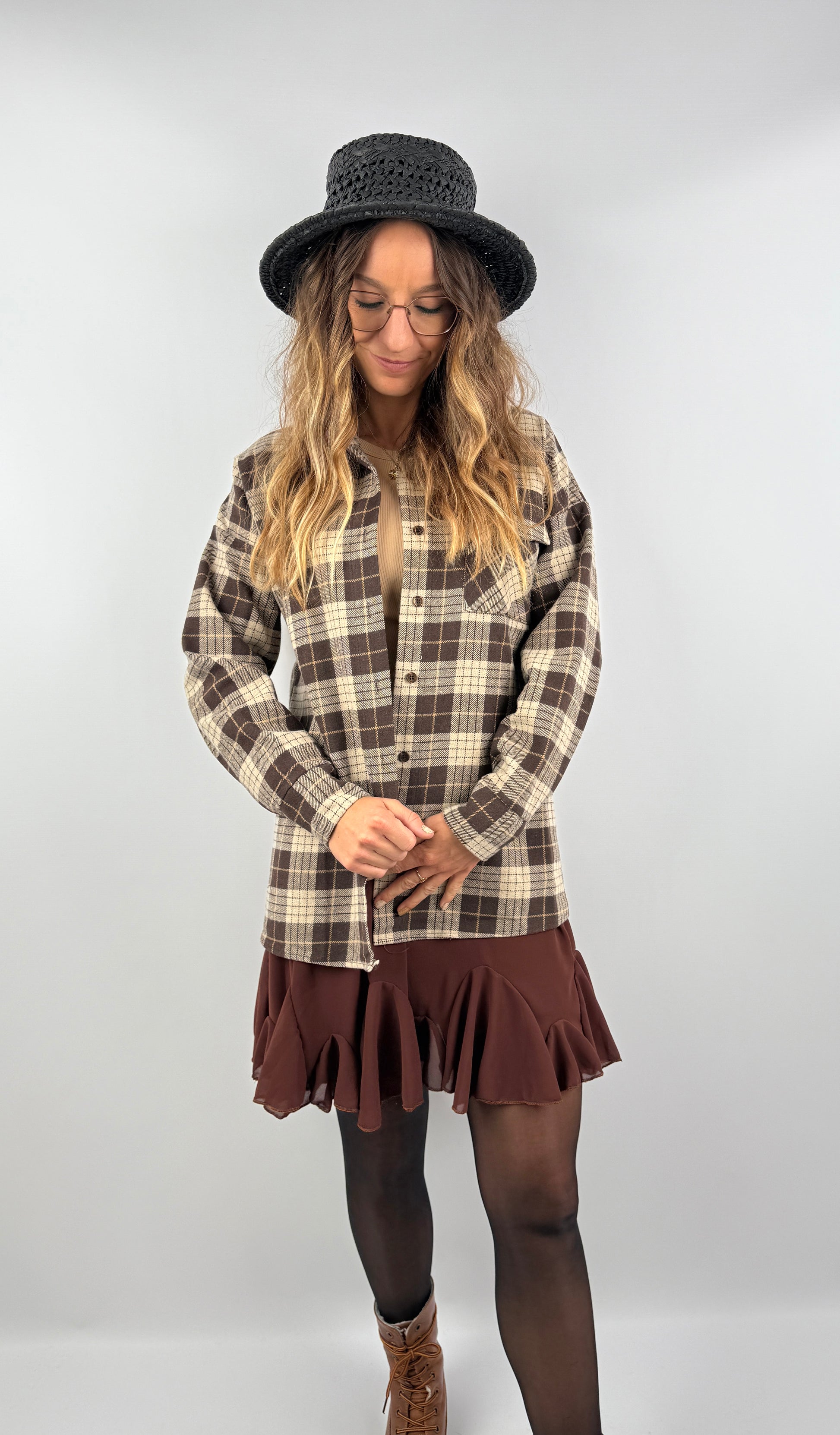 Kariertes Overshirt in warmen Brauntönen, kombiniert mit Rock und beigem Top – lässiger, moderner Herbststil mit rustikalem Touch.