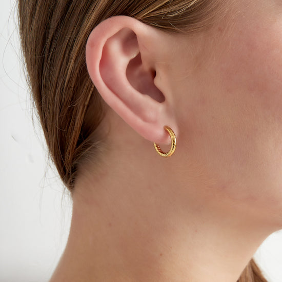 Feine dünne Creolen mit einem Relief auf der Oberfläche in Gold.