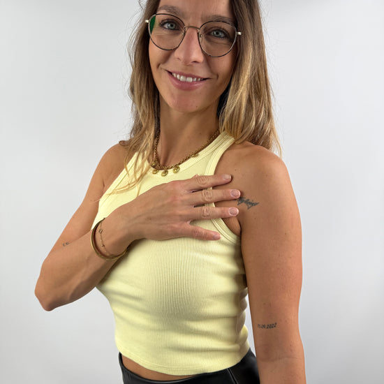 Frau trägt ein hellgelbes, geripptes Tanktop – sommerlich und modern kombiniert mit schwarzen Lederleggings.