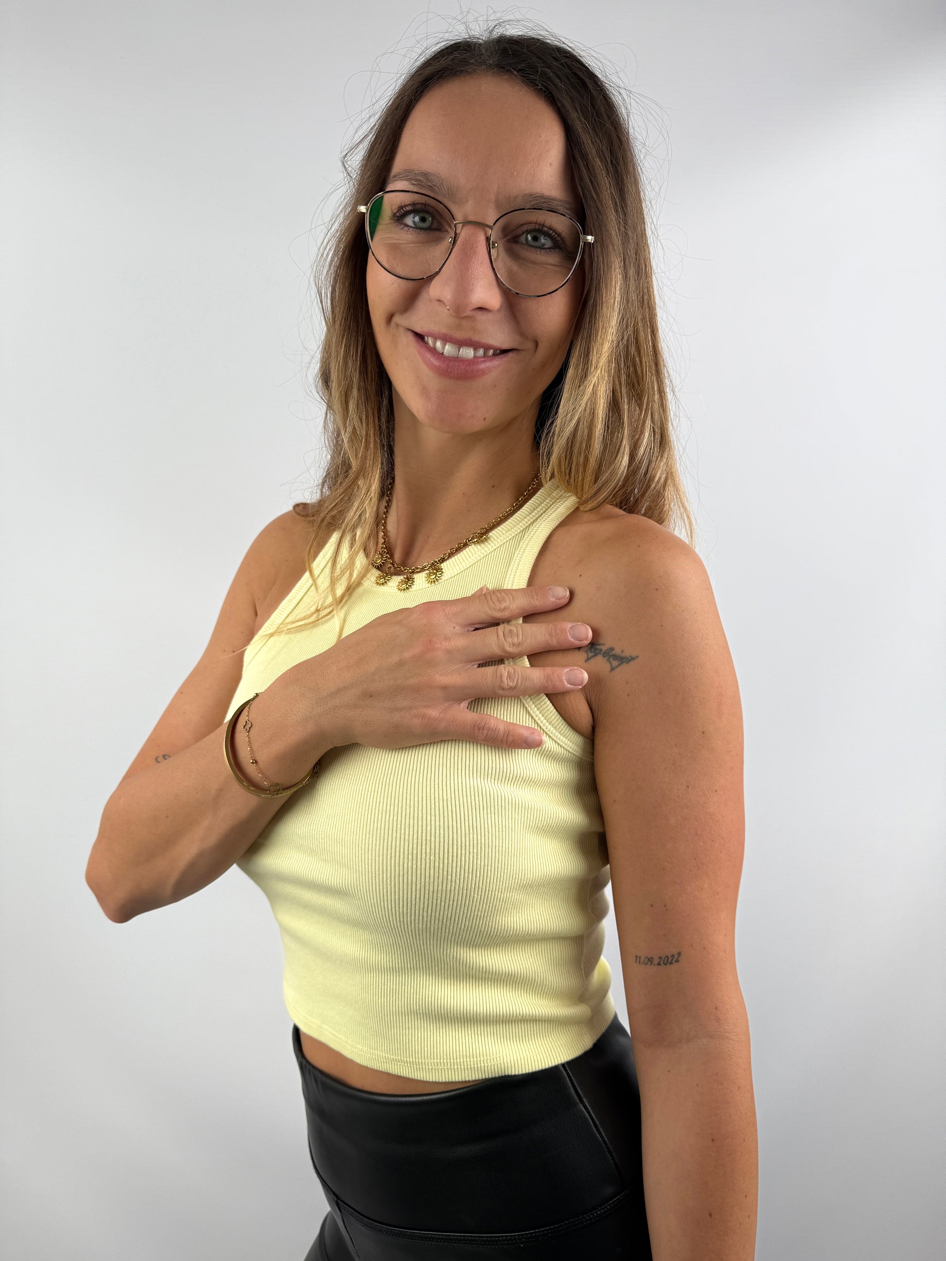 Frau trägt ein hellgelbes, geripptes Tanktop – sommerlich und modern kombiniert mit schwarzen Lederleggings.