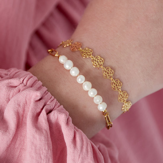 Goldenes Edelstahl Armband mit großen Kettengliedern und aneinander gereihten weißen Süßwasserperlen.