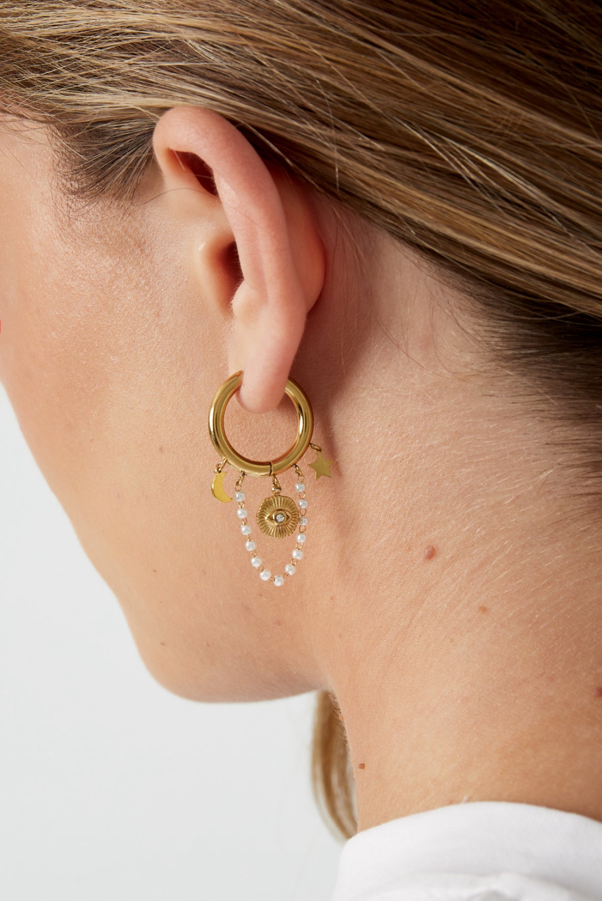 Edelstahl Creolen mit klienen Anhängern in Form von Mond, Stern und einer kleinen Perlenkette mit weißen Perlen und einem Nazar Auge in goldener Farbe.