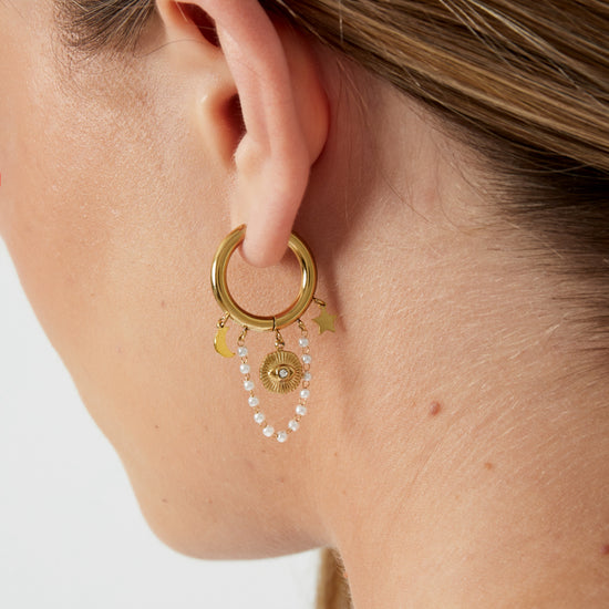 Edelstahl Creolen mit klienen Anhängern in Form von Mond, Stern und einer kleinen Perlenkette mit weißen Perlen und einem Nazar Auge in goldener Farbe.