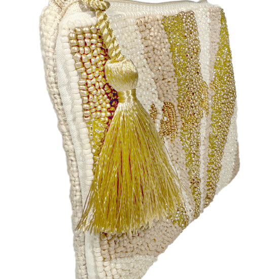 Geldbörse, die mit Perlen besetzt ist mit der Aufschrift Vacay und einem Wimpel am Reißverschluss in der Farbe beige.