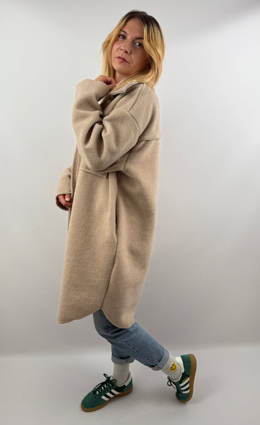 Frau trägt oversized Mantel in Dunkelbraun, seitliche Ansicht, kombiniert mit Jeans und Sneakern.