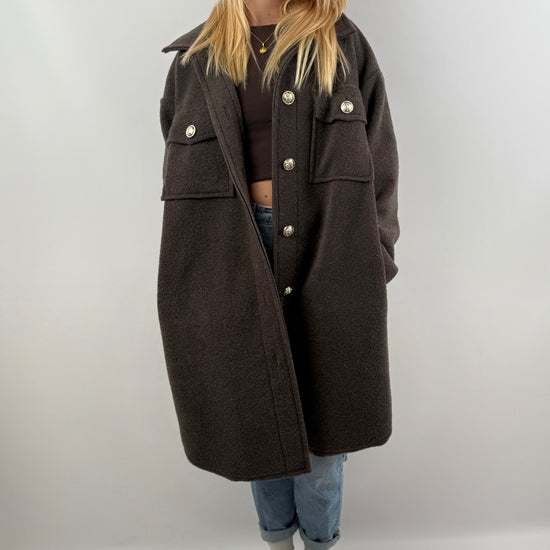 Frau trägt oversized Mantel in Dunkelbraun, kombiniert mit Jeans und grünen Sneakern, herbstliches Outfit.