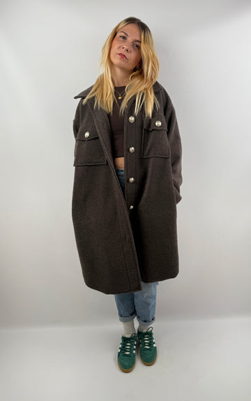 Frau trägt oversized Mantel in Dunkelbraun, kombiniert mit Jeans und grünen Sneakern, herbstliches Outfit.