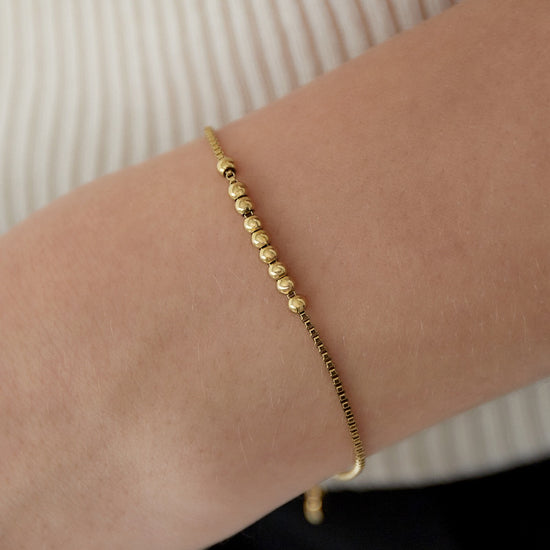 Vergoldetes Kugel-Armband in Nahaufnahme auf weißem Hintergrund.