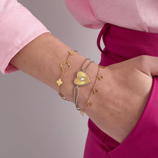Kleeblatt-Armband in Gold kombiniert mit weiteren Armbändern am Handgelenk
