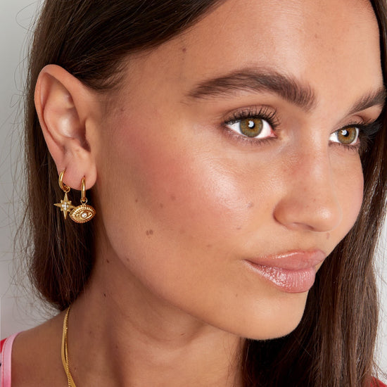 Frau trägt goldene Evil Eye Creolen im modernen Ear-Party-Look