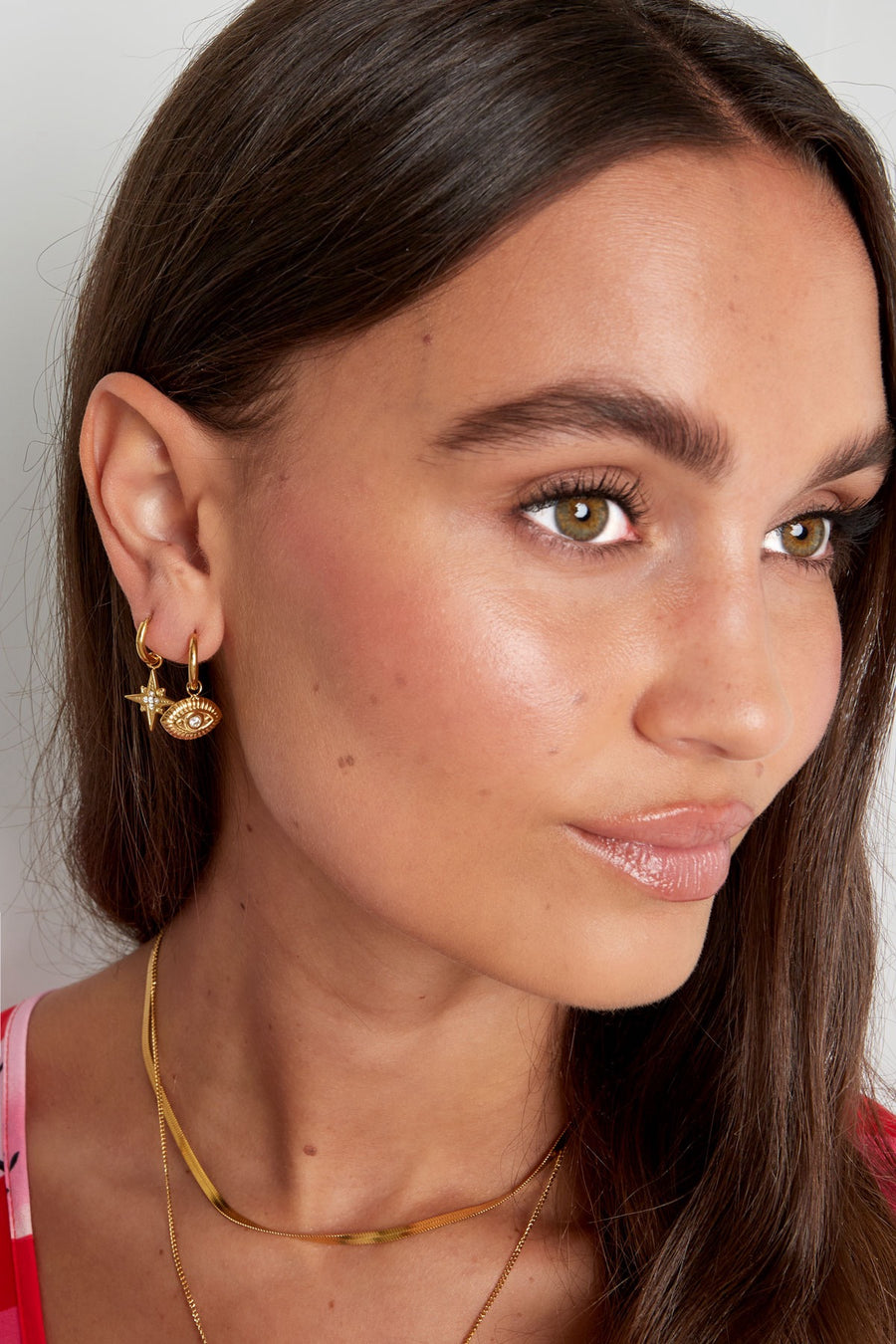 Frau trägt goldene Evil Eye Creolen im modernen Ear-Party-Look