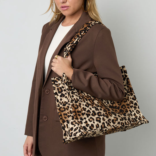 Frau trägt Leopard Shopper Bag über der Schulter, kombiniert mit braunem Blazer.