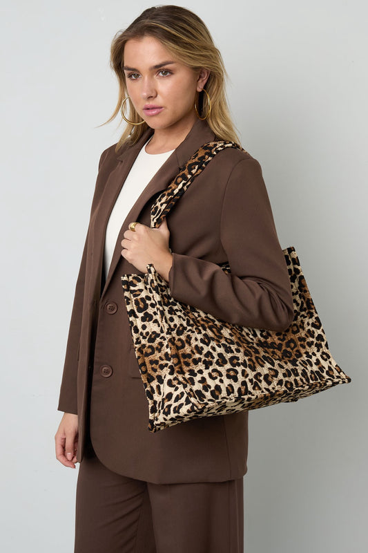 Frau trägt Leopard Shopper Bag über der Schulter, kombiniert mit braunem Blazer.