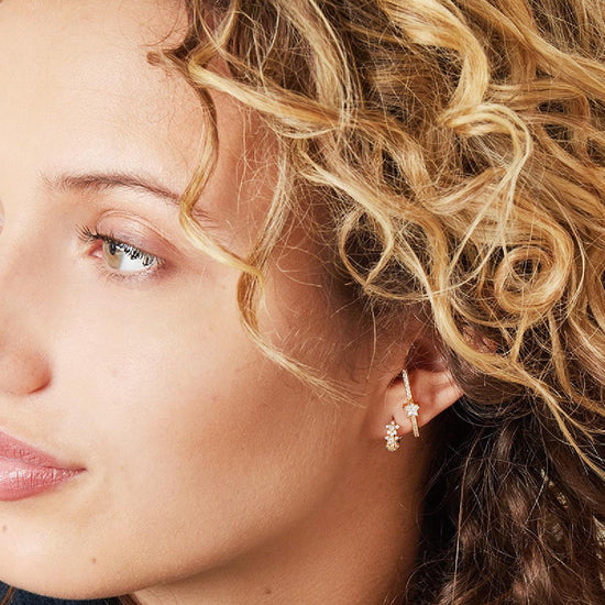 Frau trägt goldene Mini-Creolen mit Zirkonia-Besatz – stilvolles, elegantes Outfit.