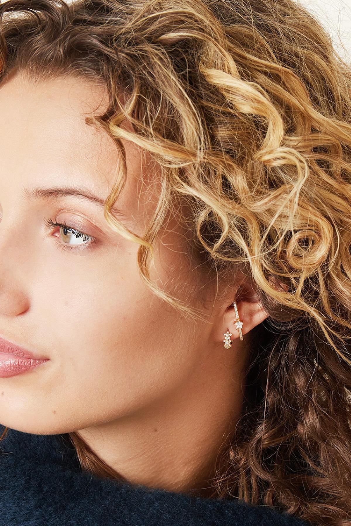 Frau trägt goldene Mini-Creolen mit Zirkonia-Besatz – stilvolles, elegantes Outfit.