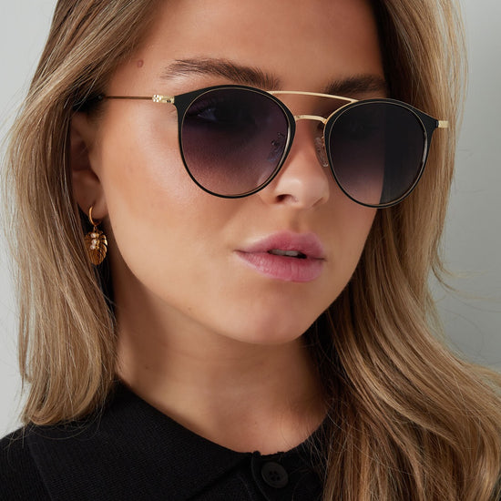 Schwarz goldene Sonnenbrille mit schwarzen Brillengläsern und roten Enden.