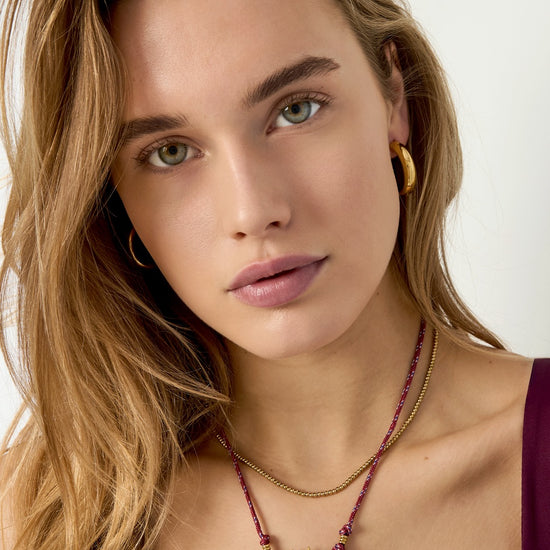 Model trägt die vergoldete Edelstahlkette Solara mit Sonnenanhänger.