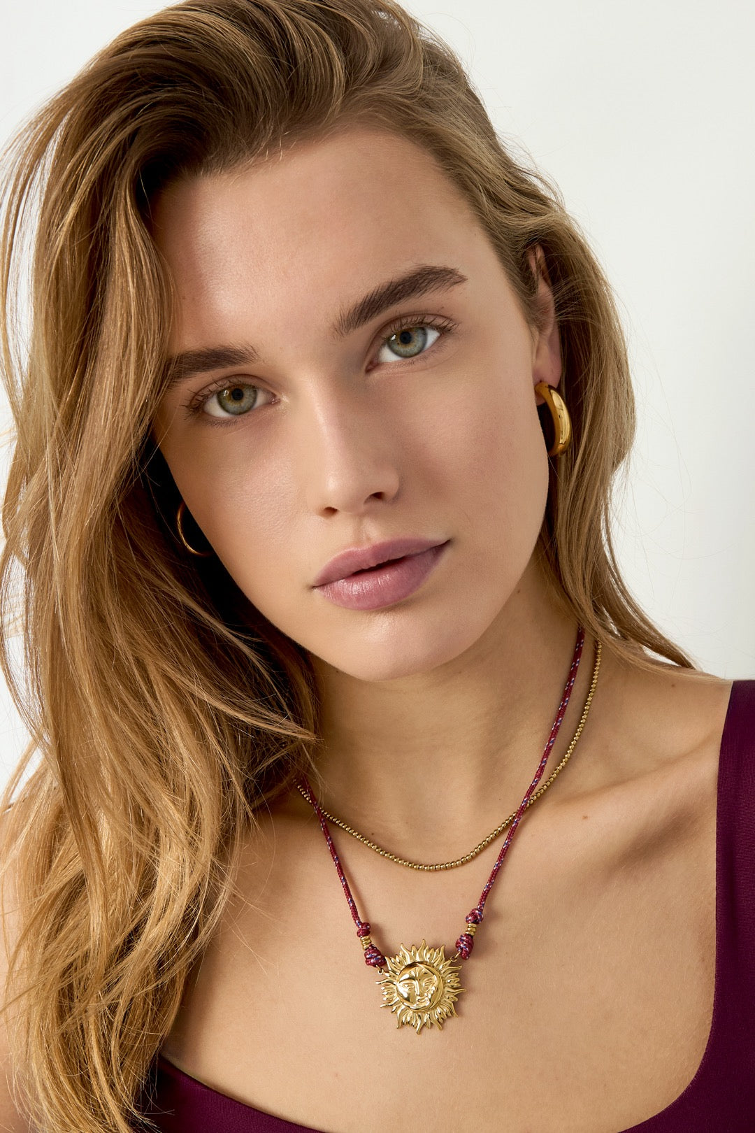 Model trägt die vergoldete Edelstahlkette Solara mit Sonnenanhänger.