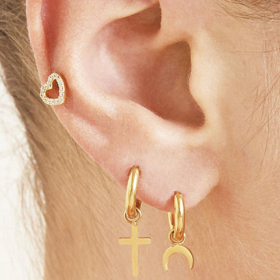 Ohr mit goldener Edelstahl-Creole und Kreuzanhänger.