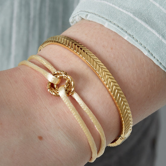 Goldener Edelstahl-Herringbone-Armreif am Handgelenk.