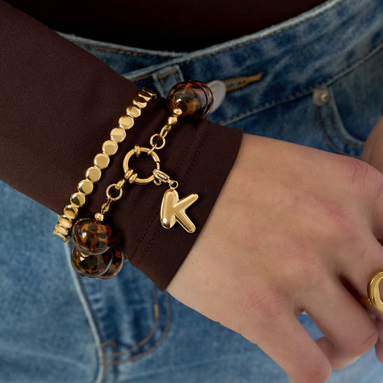 Handgelenk mit Layering-Armbändern, darunter das Animal-Print-Perlenarmband.