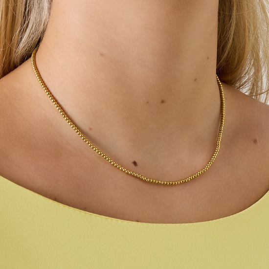 Goldfarbene Kugelkette aus vergoldetem Edelstahl am Hals getragen