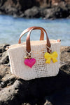 Geflochtene Strandtasche mit pinkem Herzanhänger und gelbem Schleifen Taschenanhänger