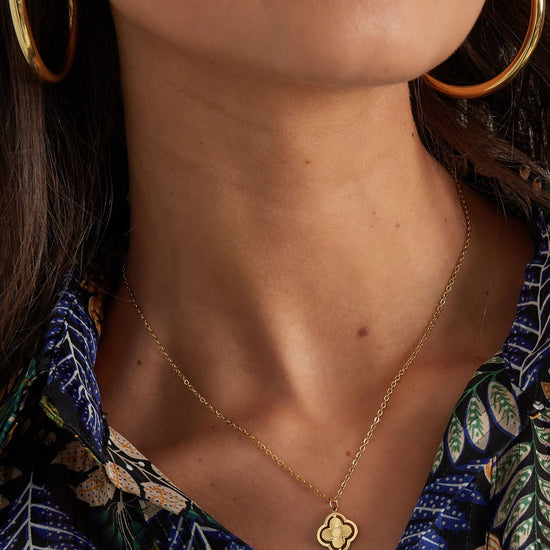 Nahaufnahme: Frau trägt eine zarte goldene Kleeblatt-Kette mit elegantem Anhänger.