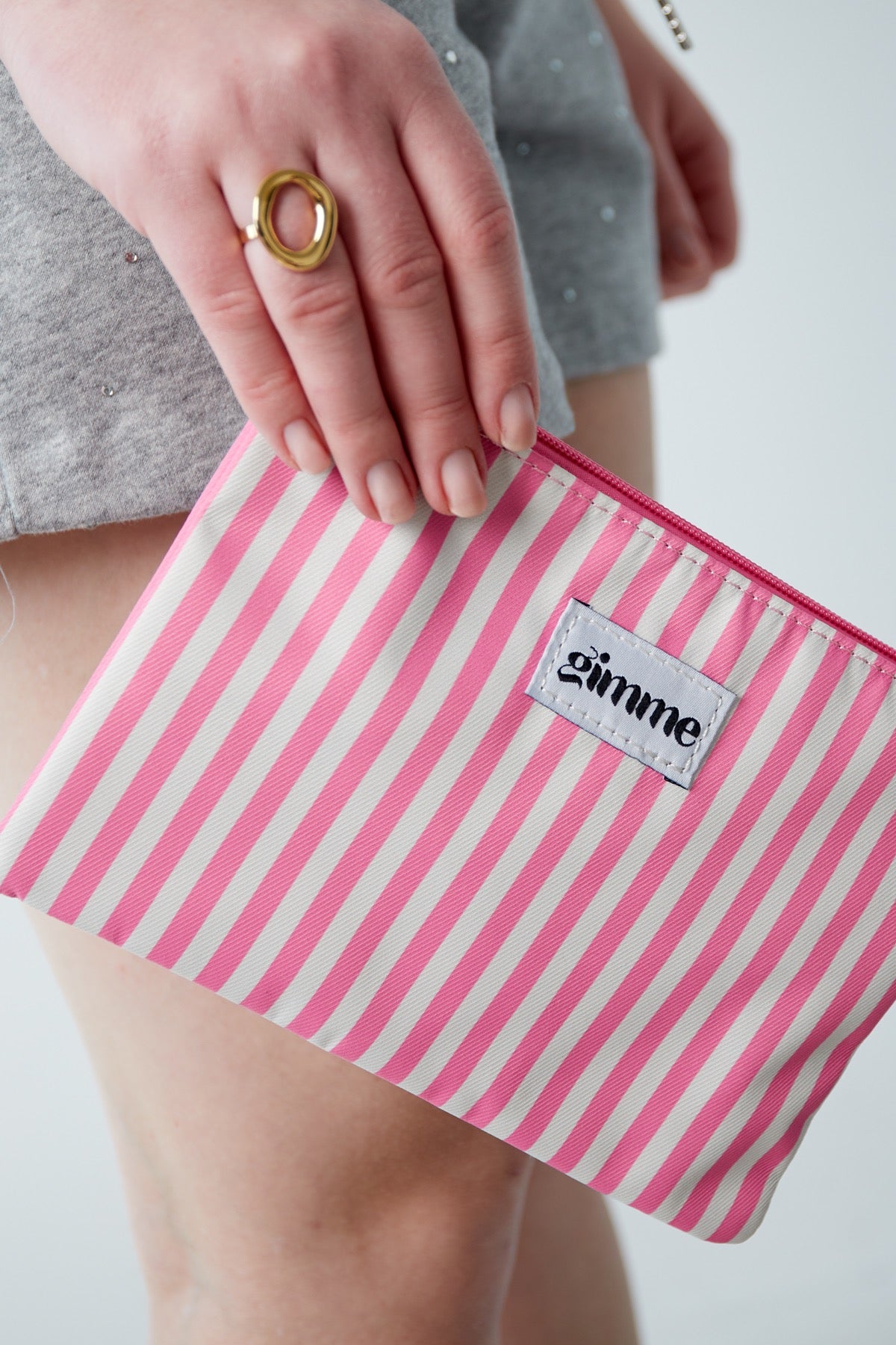 Pink weiß gestreifte flache Kosmetiktasche mit pinkem Wimpel am Reisverschluss.