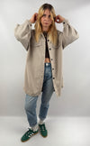 Frau trägt beige Long Hemd Jacke offen über Jeans und Crop Top.