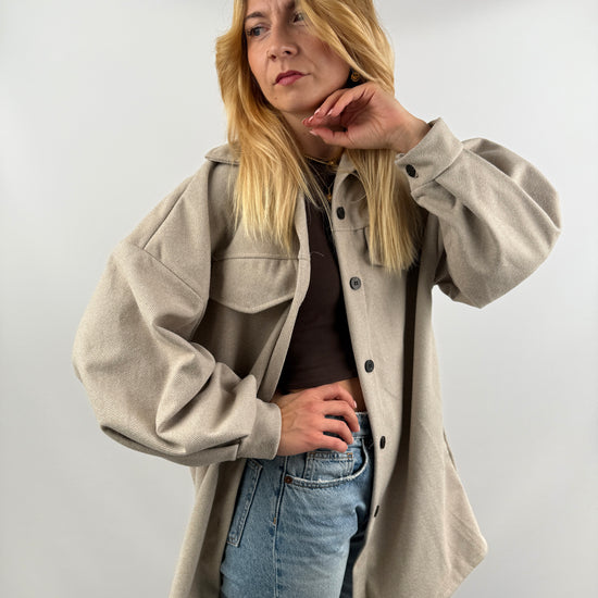 Frau trägt beige Long Hemd Jacke seitlich, mit Jeans kombiniert.