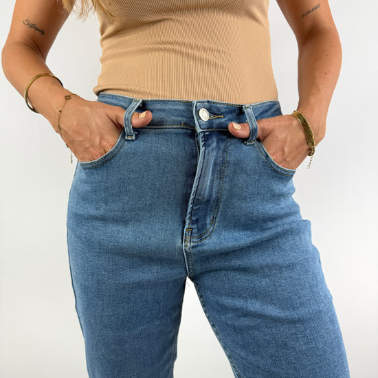 Nahaufnahme einer hellblauen High-Waist-Jeans mit klassischem Schnitt, kombiniert mit einem beigefarbenen Ripp-Top – clean und modern gestylt.