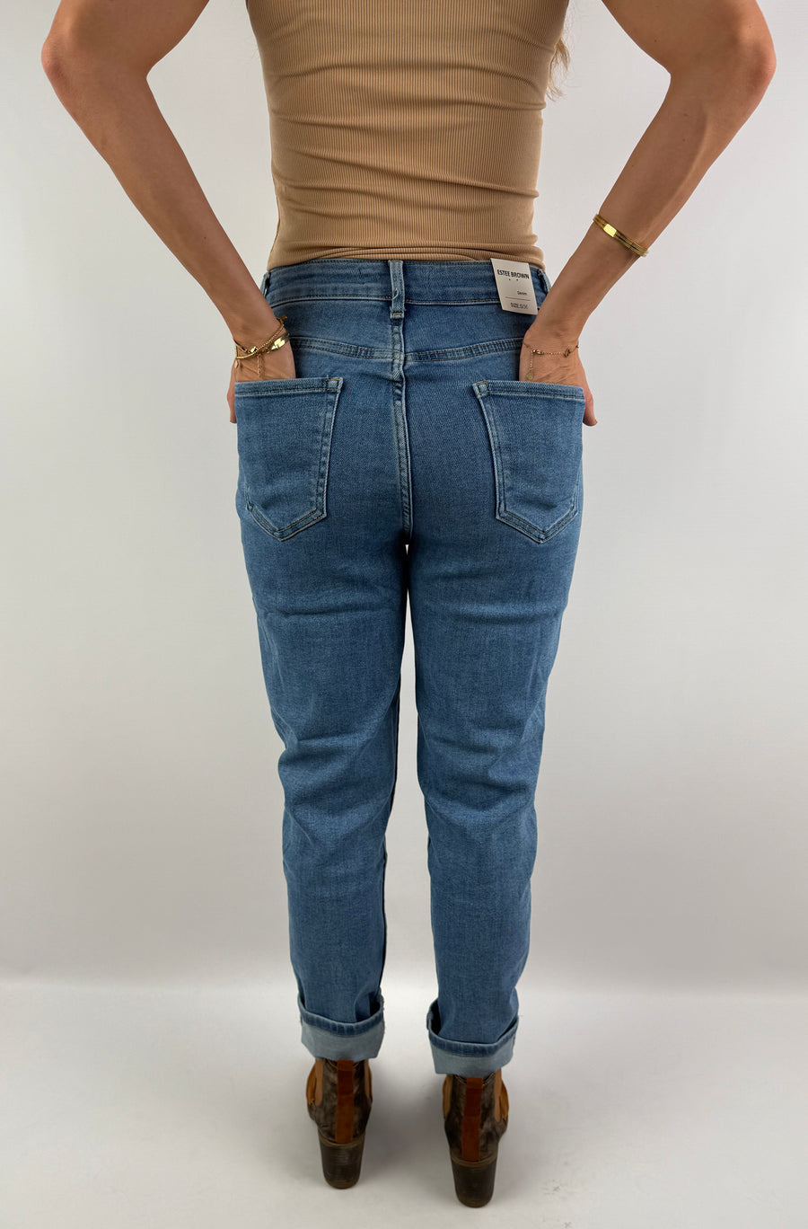 Rückenansicht einer figurbetonten High-Waist-Jeans in hellblauem Denim, kombiniert mit einem beigefarbenen Top – lässig und zeitlos.