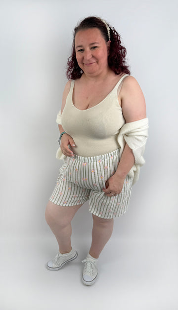 Kurze weiße Musselin Shorts mit olive farbenen Streifen und rosa Blümchen.