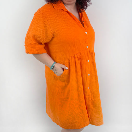 XL Musselin Kleid mit Knopfreiehe und seitlichen Taschen und 3/4 Ärmeln in der Farbe Orange.