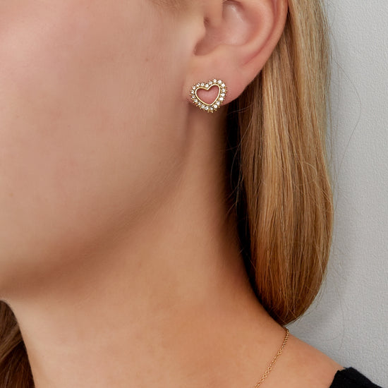 Gold farbener Ohrstecker in Form eines hohlen Herzes, wessen Rand mit zarten Zirkonia Steinen besetzt ist.