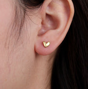 Goldene kleine Ohrstecker in Herzform.