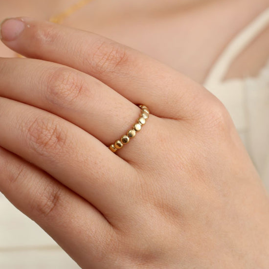 Größenverstellbarer Edelstahlring mit platt gedrückten Kugeln in goldener Farbe.